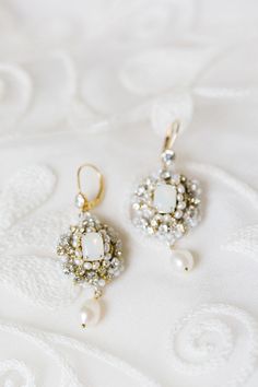 two pairs of earrings sitting on top of a white cloth