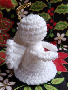 a crocheted angel ornament sitting on top of a floral table cloth