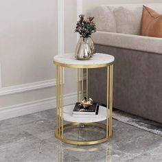 a white marble and gold metal end table with flowers on the shelf next to it