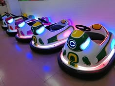 several bumper cars are lined up in a row on the floor with colorful lights around them