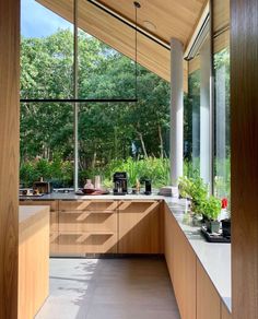 an open kitchen area with wooden cabinets and counter tops, along with large windows overlooking the trees