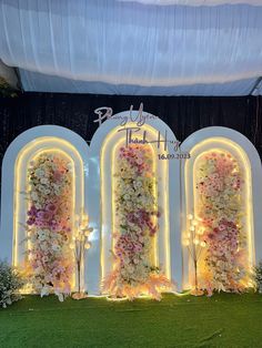 an outdoor event with flowers on the wall and white arches at the entrance to the venue