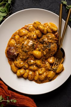 a white plate topped with meat covered in sauce and garnished with green leaves