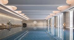 an indoor swimming pool with blue tiles and white ceiling lights on either side of it