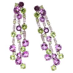 Alex Jona design collection, hand crafted in Italy, chandelier clip-on earrings featuring 7.57 carats of amethysts, 5.34 carats of peridots and 0.37 carats of white diamonds. Dimensions : L 2.12 in x W 0.59 in x D 0.14 in - L 2.12 mm x W 15 mm X D 3.6 mm. Alex Jona jewels stand out, not only for their special design and for the excellent quality of the gemstones, but also for the careful attention given to details during all the manufacturing process. Alex's passion for jewels flows in splendid pieces entirely hand-crafted according to the best goldsmith Italian tradition. This piece will arrive at your door beautifully gift wrapped in Alex Jona boxes, put inside an elegant pouch or jewel box. OUR STORY Walking past number eight of Via Bogino, Palazzo Balbo di Vinadio, a baroque building b Elegant Pouch, Gold Chandelier Earrings, Gold Chandelier, Design Collection, Manufacturing Process, Special Design, White Diamonds, Chandelier Earrings, White Diamond