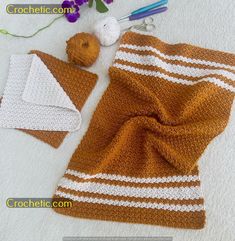 there is a crocheted brown and white blanket on the floor next to two balls of yarn