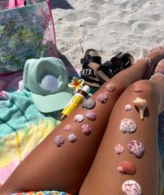 a woman laying on the beach with her legs covered in shells and sunscreens