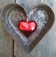 a heart shaped metal container hanging on a wooden wall