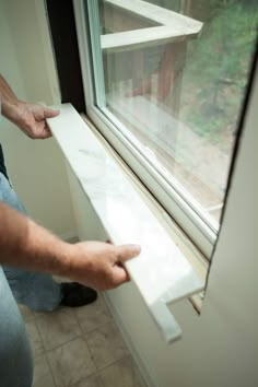 a man is holding the edge of a window sill to open it with his hand