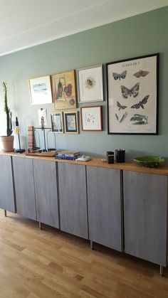 an empty room with several framed pictures on the wall and wood flooring in front of it