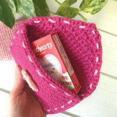 a pink crocheted hat with a tube of toothpaste in the pocket