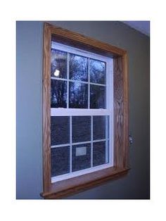 an empty window in the corner of a room with blue walls and trees behind it