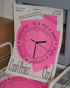 a pink clock sitting on top of a white chair next to a pile of papers