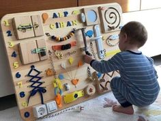 a young child playing with a wooden peg board that has various necklaces and bracelets on it