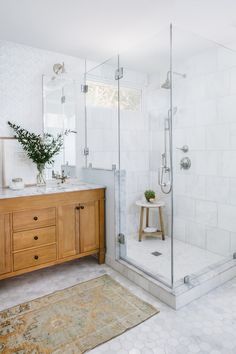 a bathroom with a wooden cabinet and white tile walls, along with a walk in shower