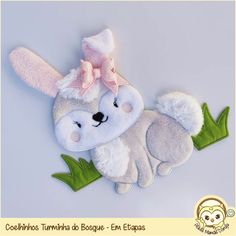 a stuffed animal with a pink bow on it's head and green leaves around its neck