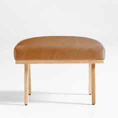 a wooden bench with a tan leather seat cover on the top and bottom legs, in front of a white background