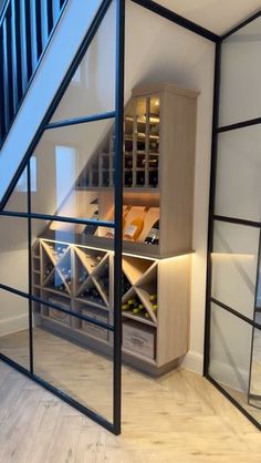 a wine cellar in the corner of a room with glass walls and stairs leading up to it