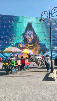 a mural on the side of a building with people walking by and bicycles parked in front