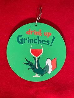 a green sign that says drink up grinches with a red wine glass in it