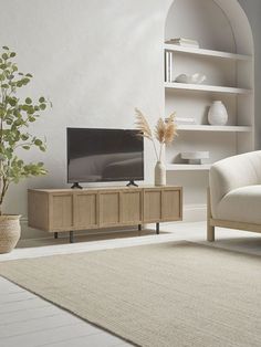 a living room with a couch, chair and television on the stand in front of it