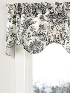 a window curtain with black and white toiler print on the valance, in front of a window