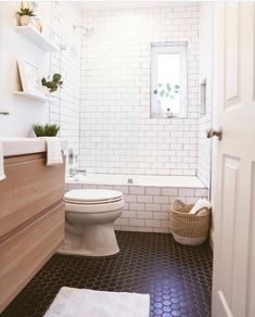 a white toilet sitting next to a bath tub in a bathroom with black and white tile