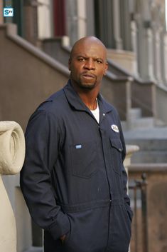 a man standing in front of a building with his hands in his pockets and looking at the camera