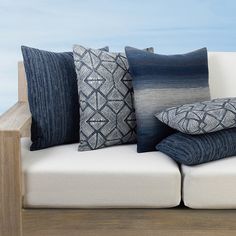 a white couch with pillows on top of it and a wooden table in the background