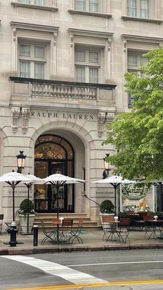 an old building with tables and umbrellas outside