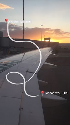 an airplane wing with the sun setting in the background