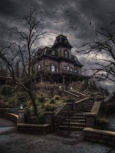 an old house with stairs leading up to it and dark clouds in the sky above