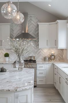 a kitchen with white cabinets and marble counter tops