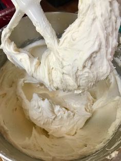 a metal bowl filled with whipped cream on top of a table