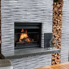 an outdoor fireplace with logs stacked on the sides and firewood in the back ground