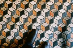 a person standing on top of a tiled floor next to a pair of black shoes