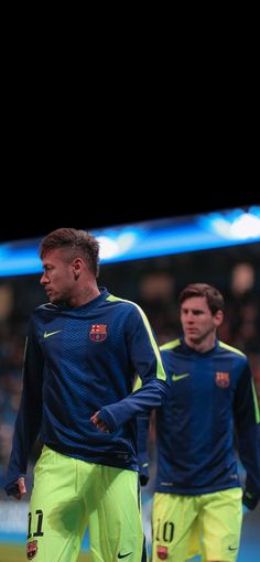 two soccer players in blue and yellow uniforms are walking on the field during a game