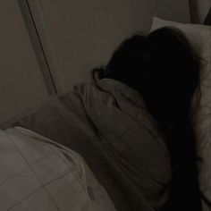 a person laying in bed with their head on the pillow