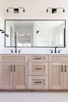 a bathroom with double sinks and large mirror above it's countertop, along with two lights on either side of the sink