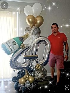 a man standing next to a large balloon shaped like the number twenty four with champagne bottles and balloons