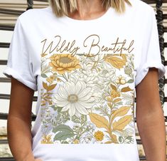 a woman wearing a white t - shirt with yellow flowers and words wild beautiful on it