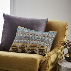 a couch with two pillows on it next to a potted plant