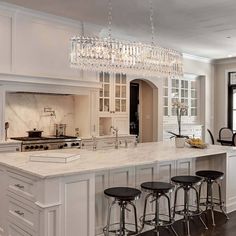 a large kitchen with an island and bar stools next to the stove top oven