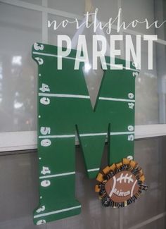 the letter m is made out of wood and has a football on it with a name that says north shore parent