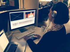 a woman sitting in front of a computer with headphones on