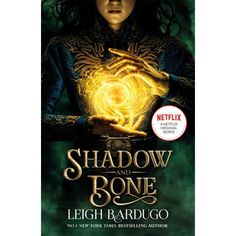 the cover to shadow and bone by leigh bardugo, with an image of a woman holding a glowing ball in her hands