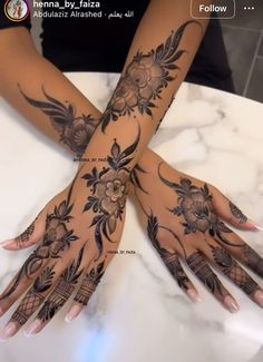 two hands with henna designs on them sitting on a marble counter top in front of a mirror