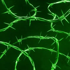 green barbed wire against a black background with the light shining on it's sides