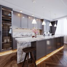 a large kitchen with marble counter tops and wooden flooring, along with two bar stools