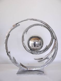 a silver sculpture on top of a metal stand with a ball in the middle of it